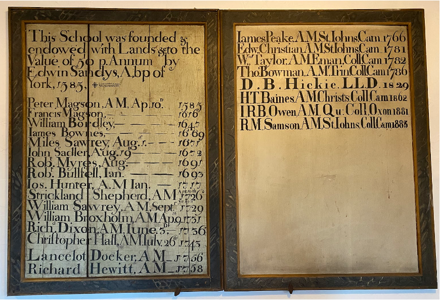 Image of a list of names of headmasters mounted onto a wall. 